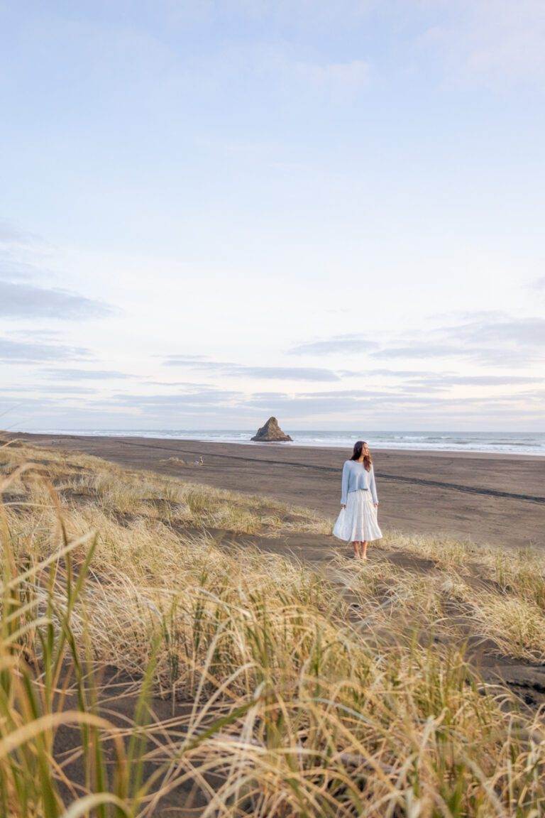 girl standing at karekare beach knowing what is it like to live in Auckland – About Page