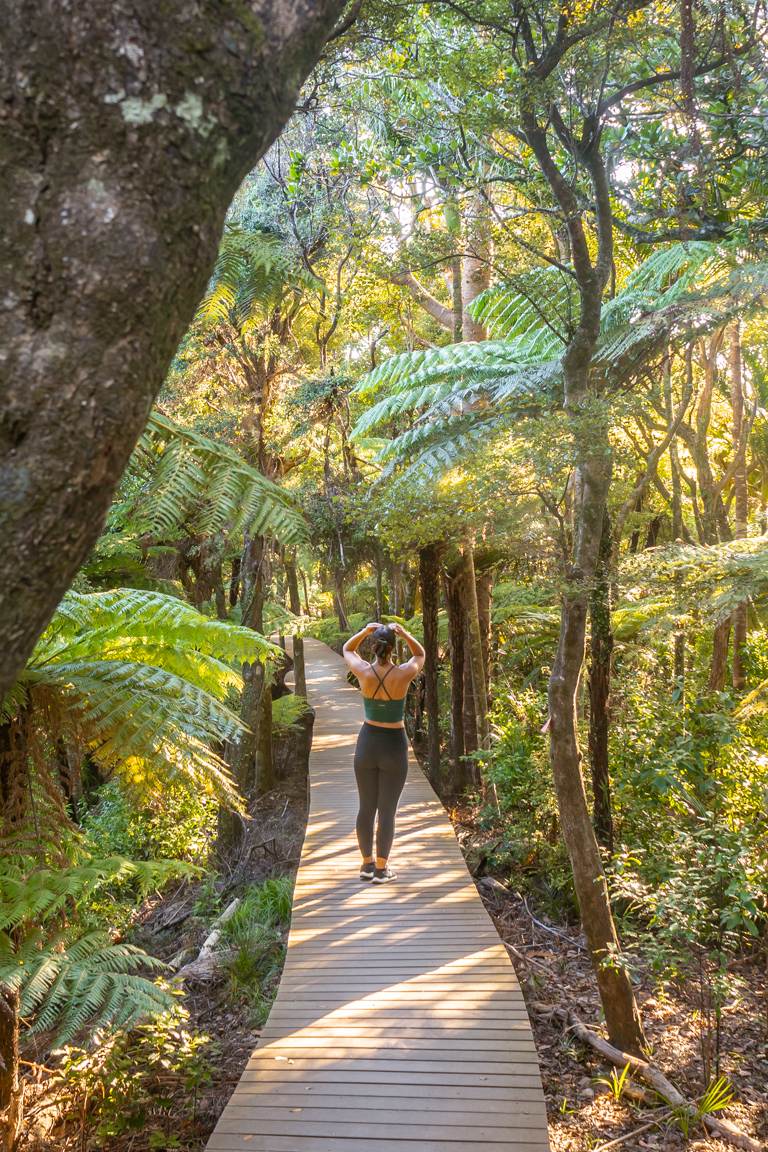 girl walking omanawanui boardwalk track through forest