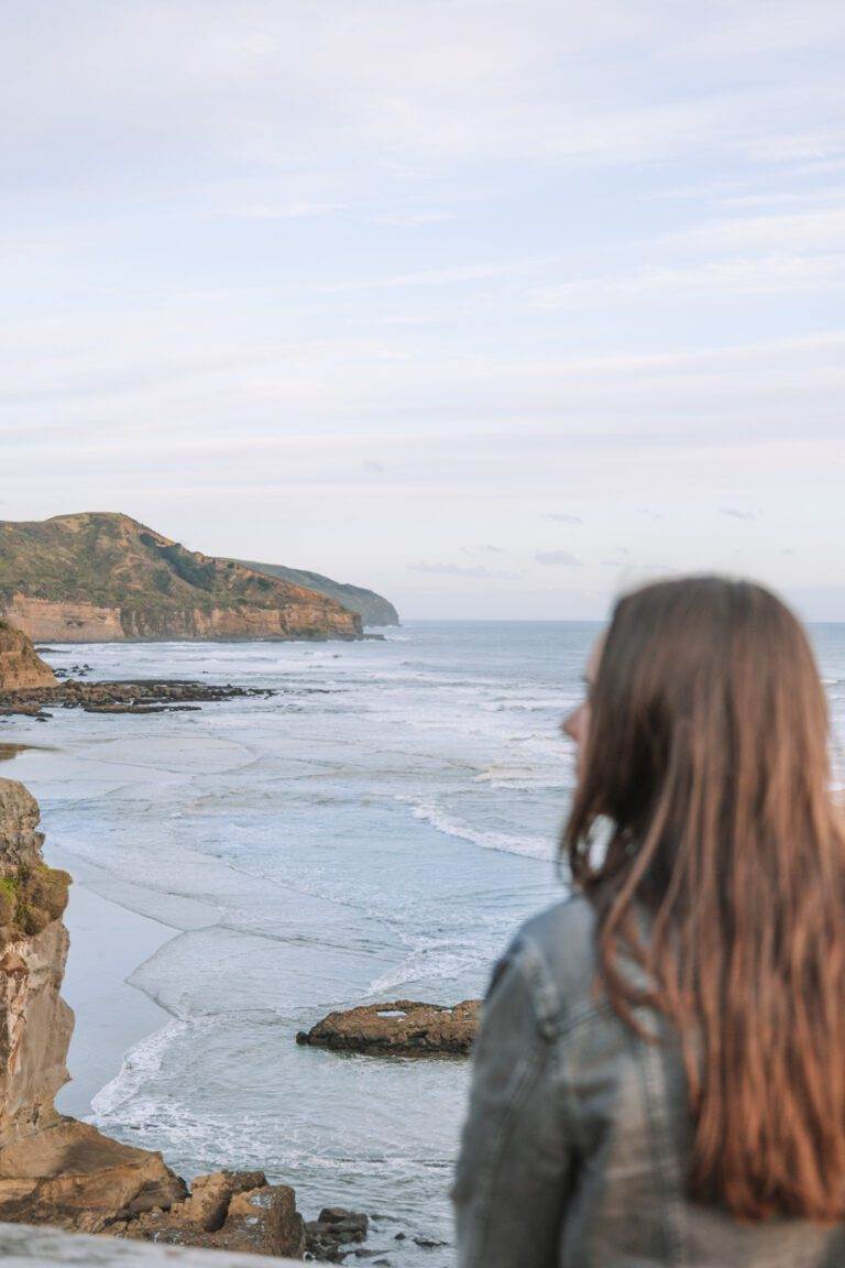 girl standing looking over muriwai beach when visiting auckland