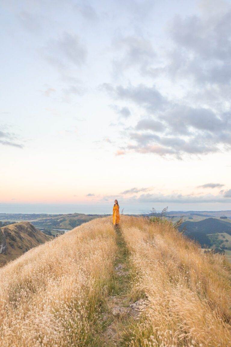 girl wrapped in blanket on top of te mata peak at sunset