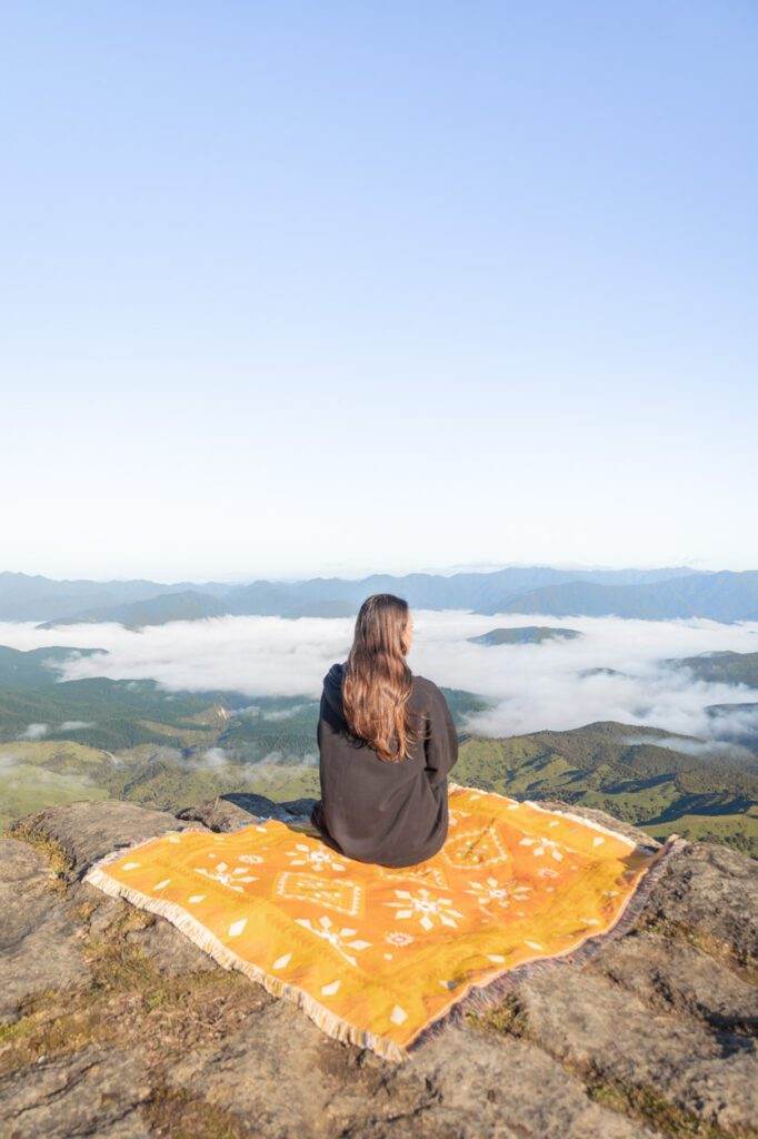 girl sitting on throw on top of rock new zealand