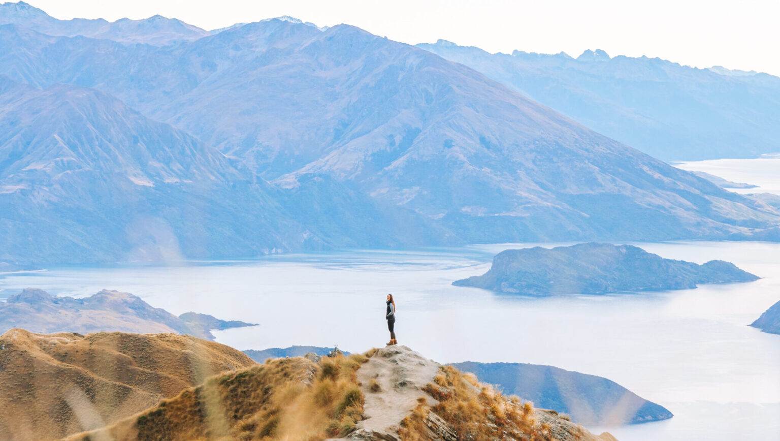 girl standing on top of Roys Peak in Wanaka New Zealand showing South Island landscape photography