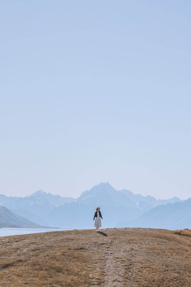 woman standing on hill in front of mount cook in autumn in the south island