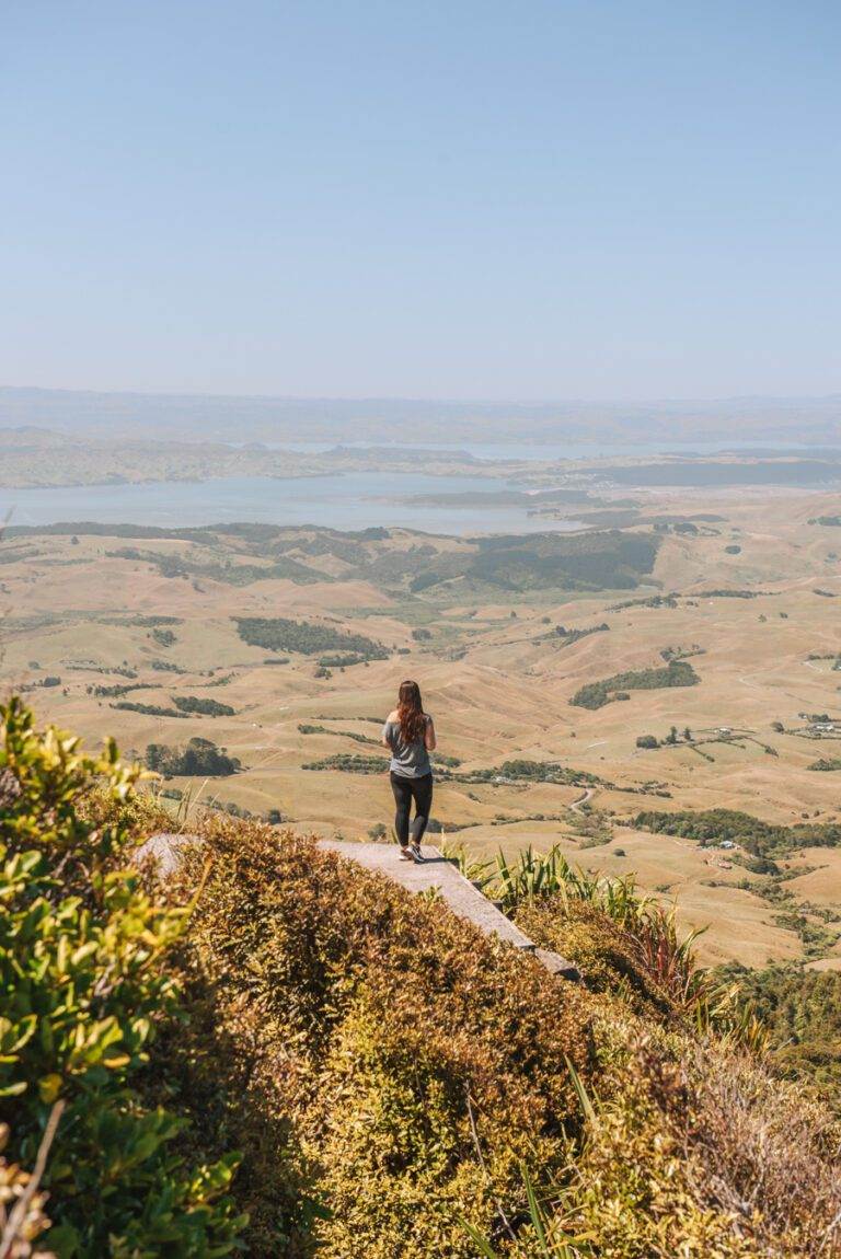 girl standing at summit of mount karioi after hiking north island new zealand