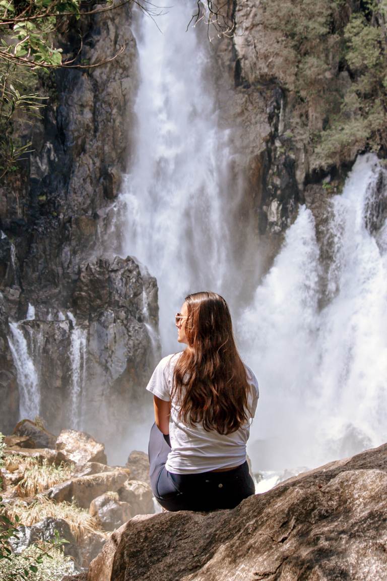 girl sitting in front of Tarawera Falls, New Zealand landscape photos