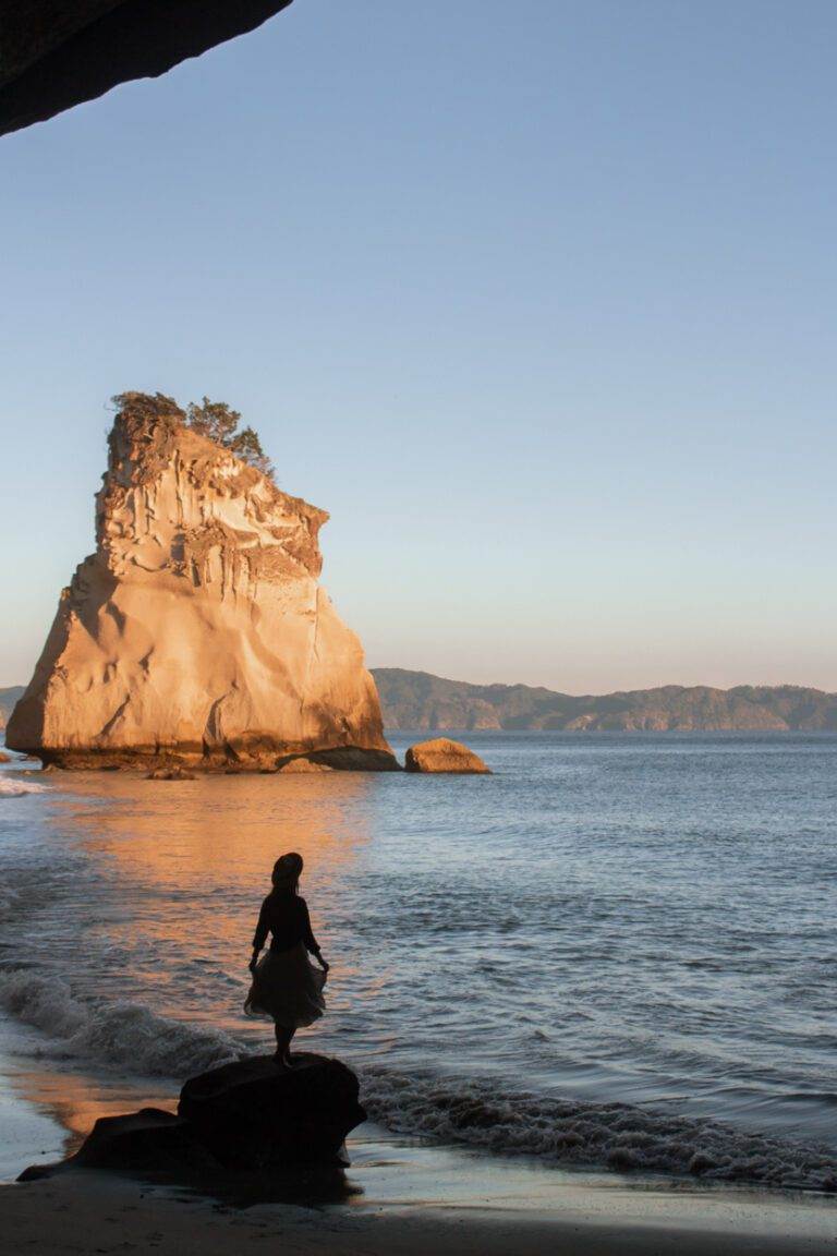 girl standing at cathedral cove at sunrise