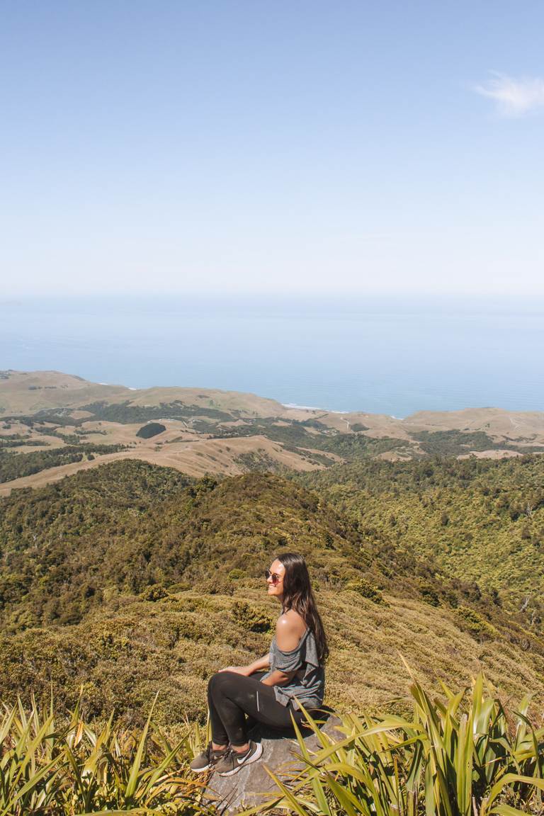 girl sitting at summit of mount karioi