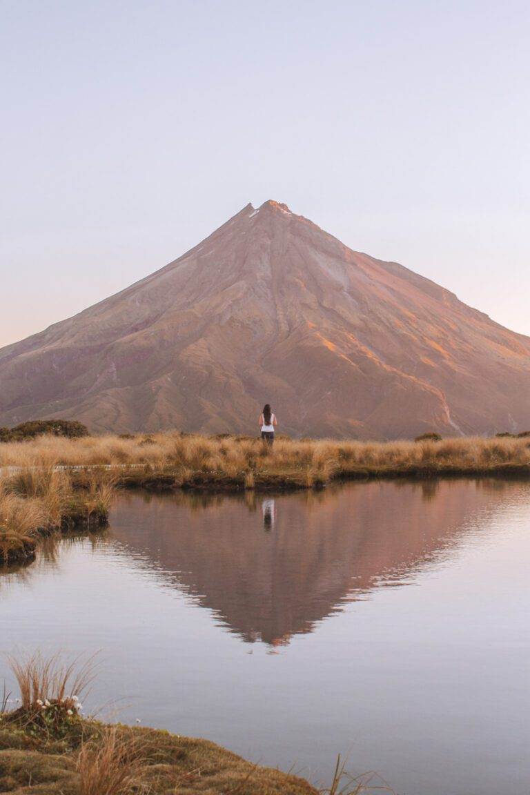 girl standing in front of mount taranaki and pouakai tarns