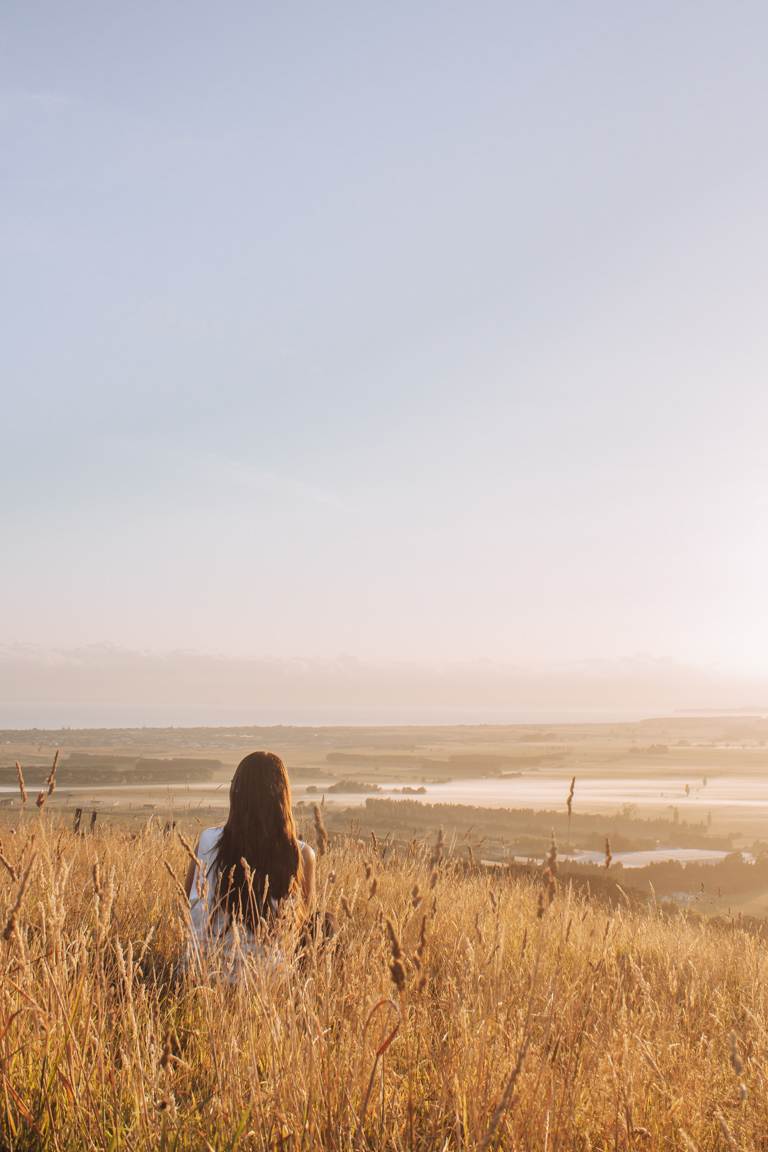 girl sitting looking out over bay of plenty from papamoa hills