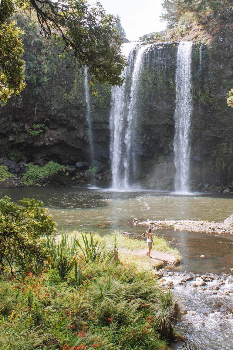 girl standing in front of new zealand waterfall