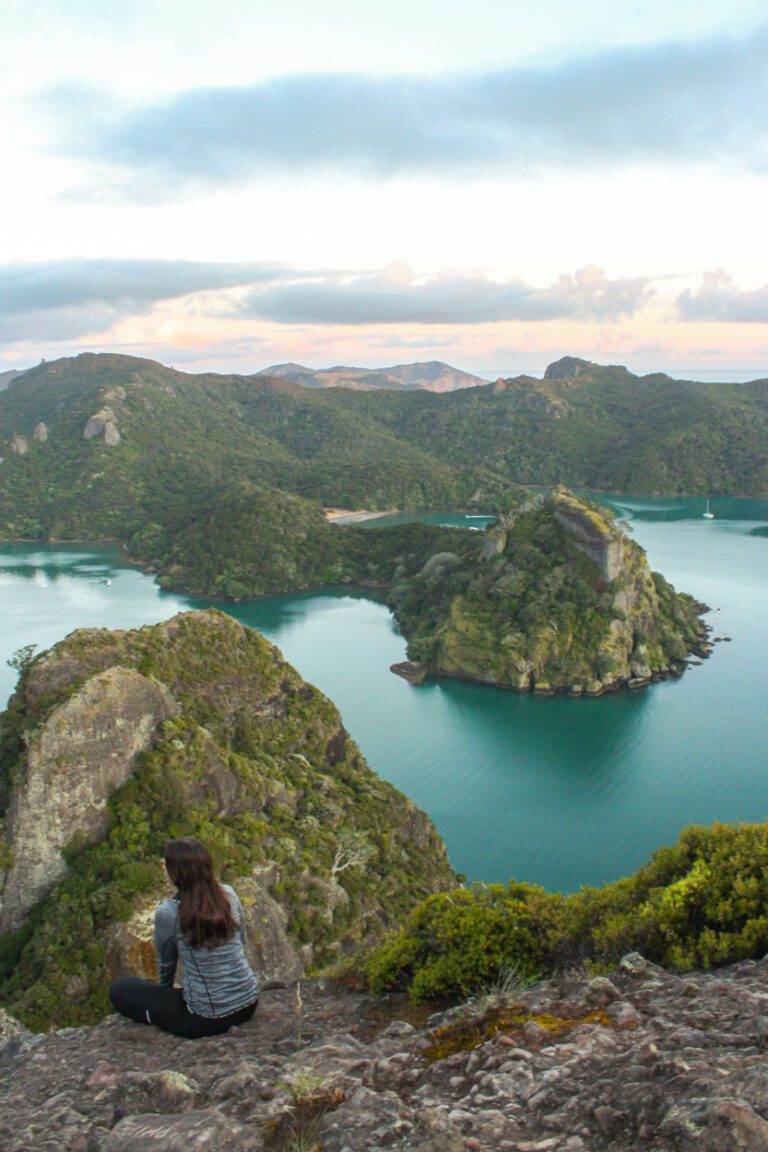 girl sitting on top of dukes nose hike lookout, northland