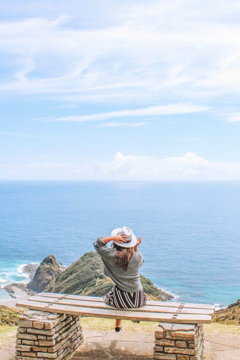 girl sitting overlooking cape reinga on northland road-trip