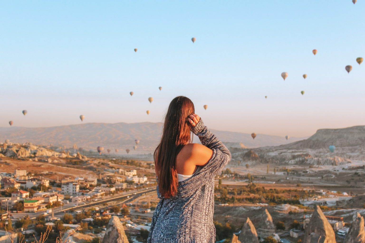 girl overlooking cappadocia hot air balloons at sunrise