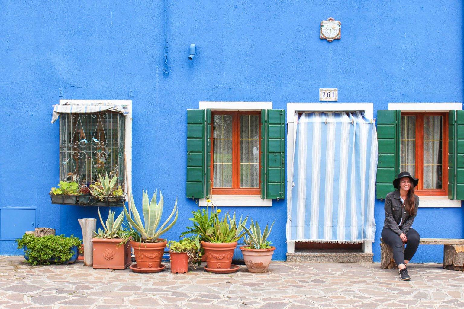 girl sitting in front of burano blue house