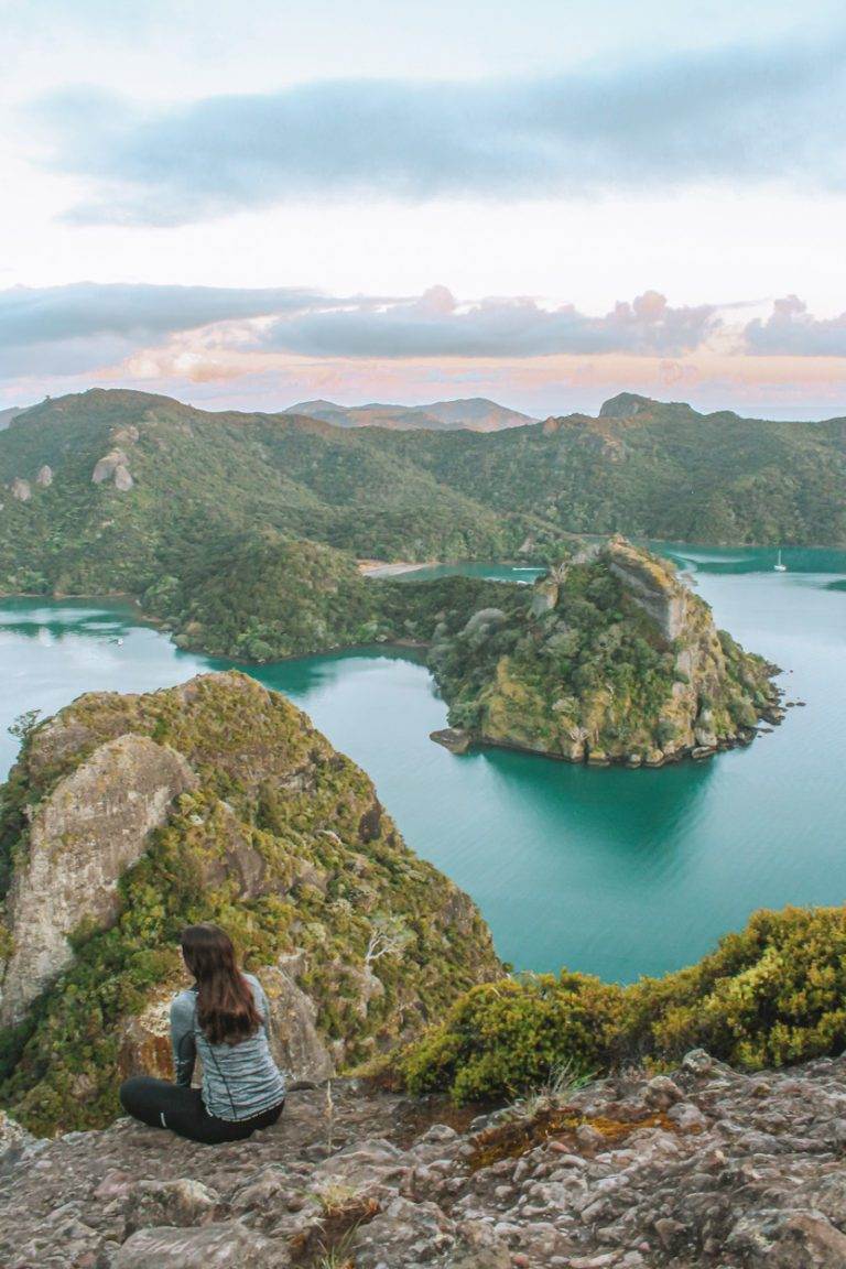 girl sitting looking out from dukes nose during summer in new zealand