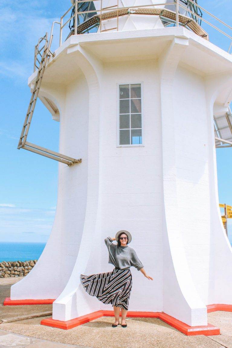 girl standing in front of cape reinga lighthouse on northland road-trip